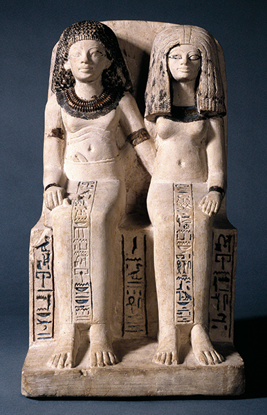 Ancient Egyptian limestone pair statue f Nebsen and His Wife Nebet-ta (ca. 1400–1352 BCE). Male and female figures seated next to each other with arms extended around each other's waists.