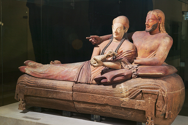Etruscan terra cotta sarcophagus lid featuring a reclining couple, the female figure wears a headpiece and braids and the male figure has a beard.