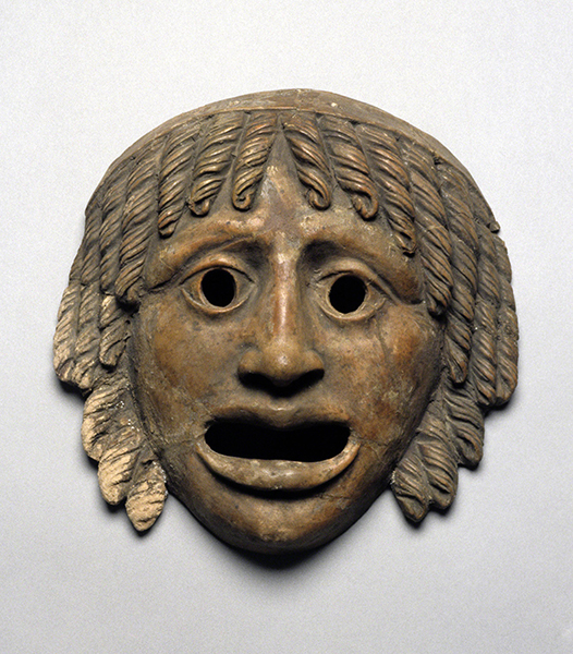 Ancient Rome, Tragic Mask, from Italy, probably first 100 years CE. Earth-colored terra cotta mask with curl, open eyes, and mouth in a pained expression.