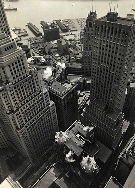 Photograph by Berenice Abbott titled Water Front from the Roof of the Irving Trust Company Building (1938). Black and white aerial photograph of New York City buildings with the waterfront visible in the upper portion.