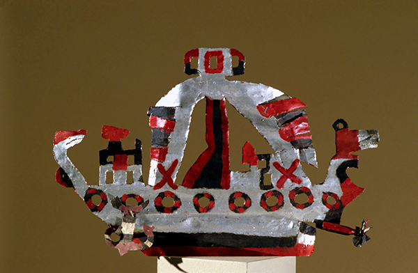 Tin sculpture by David Butler titled Ship (ca. 1950). Cut and assembled tin sculpture of a ship painted in silver, red, and black.