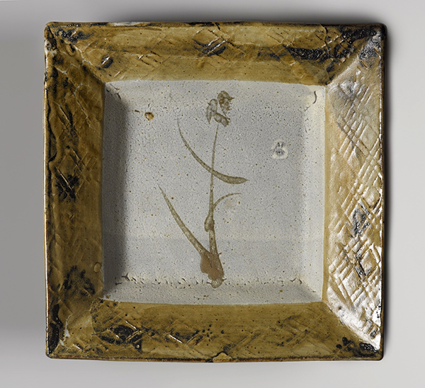 Square stoneware plate (ca. 1960) by Hamada Shōji with yellow and off-white glaze, wheat design, and incised hatching around the sides.