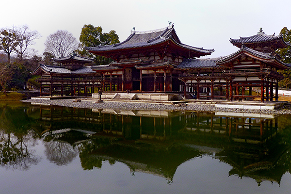 Heian Period, Byodo-in, Uji, Japan (1052–1053). Temple with large central hall and two wings with flared roof eaves and gilt phoenix sculptures on the central eaves.