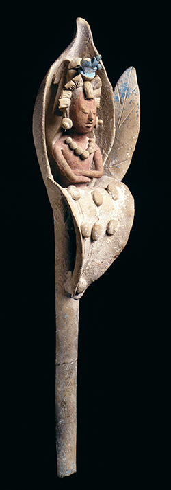 Ceramic male figure wearing a headdress and necklace emerges from a water lily.