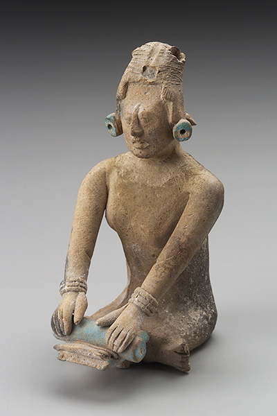 Earthenware seated female figure wearing a headdress, earspools, and bracelets grinds maize on a metate with a stone mano.