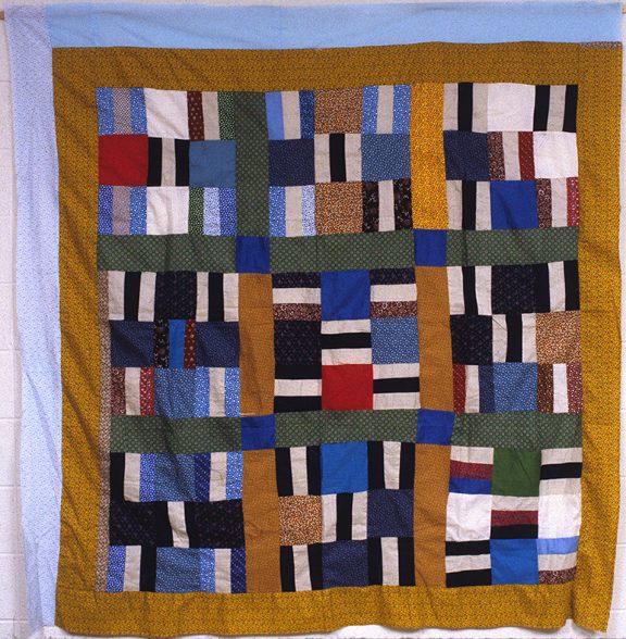 Nine-patch quilt by Plummer T. Pettway. Quilt made of nine squares comprised to white, black, blue, red, green and gold rectangles surrounded by a gold, green, and blue border.