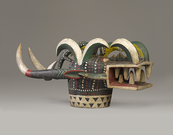 Senufo People, Mali, Kponyungo Mask, from Vallée du Bandama region, or Sikasso region, late 1900s. Wood mask in the form of a Firespitter with horns and teeth exposed painted in black, white, red, green, and yellow.