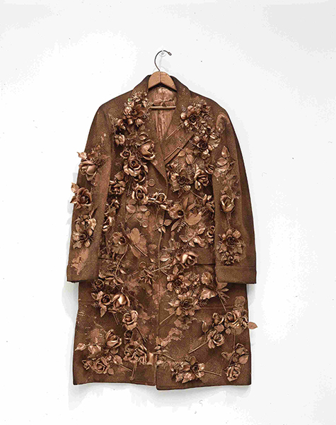 Sculpture by Yayoi Kusama titled Flowers – Overcoat (1964). Plastic flowers on a cloth coat all painted gold.