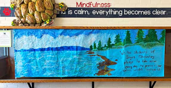 A schoolwide climate pledge banner reading, We the students of Hayes Elementary pledge to take action every day to protect our waters, wildlife, and world.
