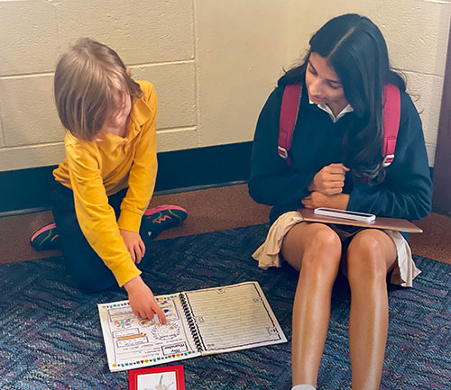 Escher, grade one, reads his illustrated story to his partnered artist, Simi, grade nine.