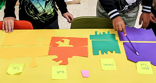 Studentsʼ abstract paper shapes are assembled in a temporary collaborative collage.