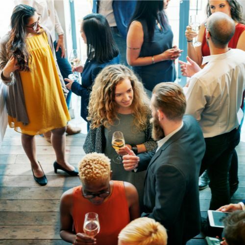 People at a social gathering holding wine glasses and talking