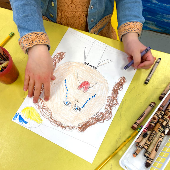 A student colors an expressive portrait reflecting sadness, the blue zone