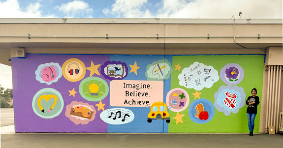 Meera Ramanathan stands beside the finished fifth-grade legacy mural.