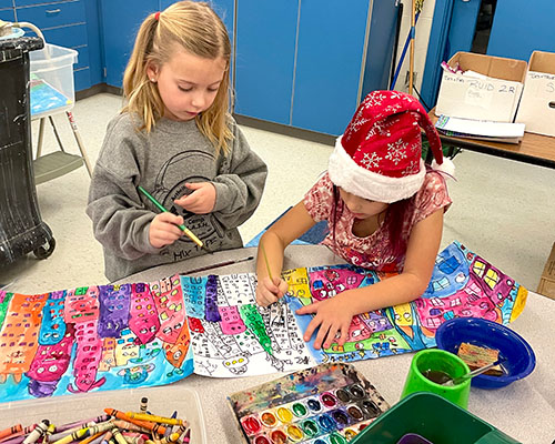 Lucy and Annalise work together on a combined cityscape watercolor painting.