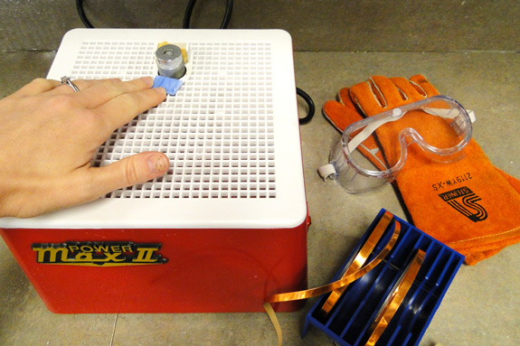 A student uses a glass grinder to shape the edges of their stained-glass piece.